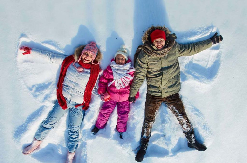 Family of three making snow angels in Lake Chelan