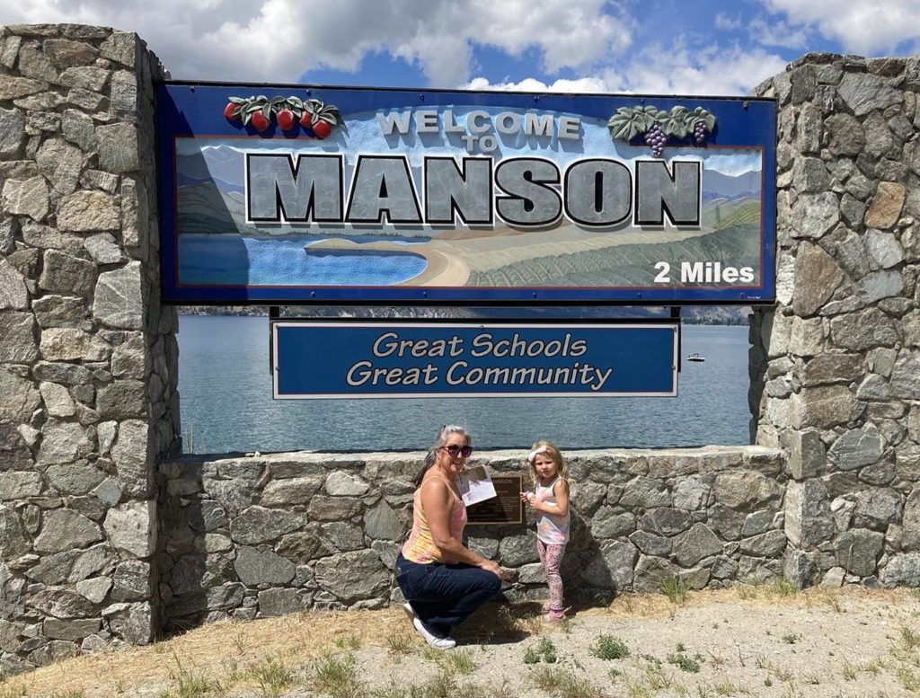 Kim in front of the Welcome to Manson sign