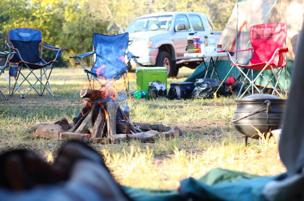 A campsite set up with a fire pit, tents, and lawn chairs