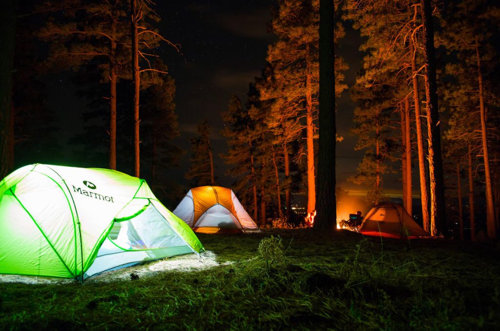 Two tents set up for camping at night with lanterns