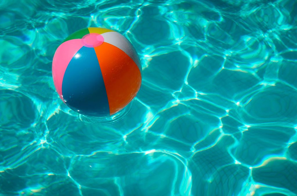 Blow up beach ball floating in a pool during a summer day