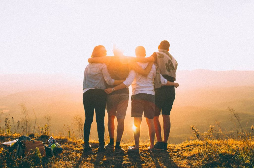 Family of four embracing one another in front of a sunset