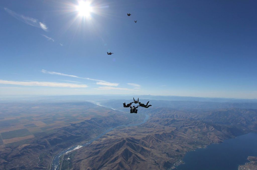 People skydiving over Lake Chelan during a clear sky day