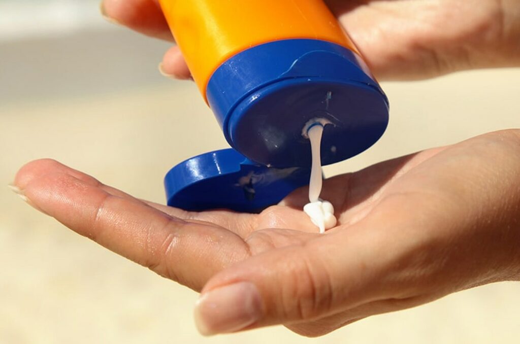 A woman's hand pouring sunscreen in her other hand