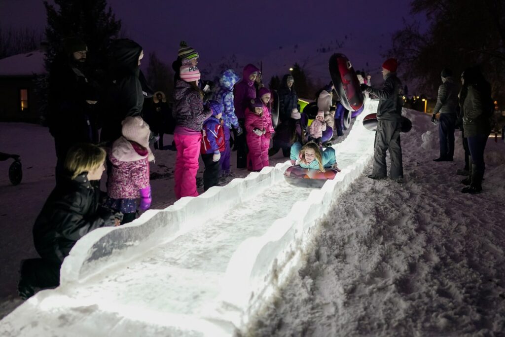 Children sliding down a slide made of ice during Winterfest 2023 in Lake Chelan