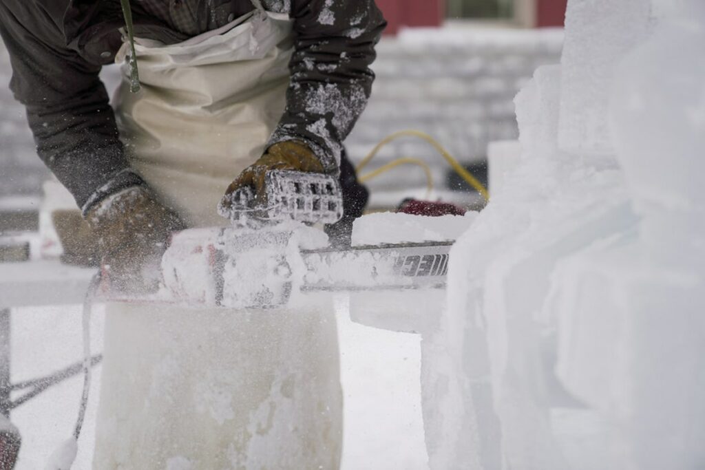 Person carving out ice with a chainsaw during Winterfest 2023 in Lake Chelan